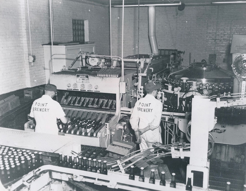 Brewery workers operate equipment inside the brewery